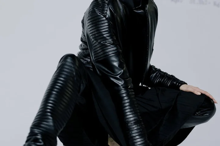 Person wearing a black leather outfit crouching, illustrating leather care.