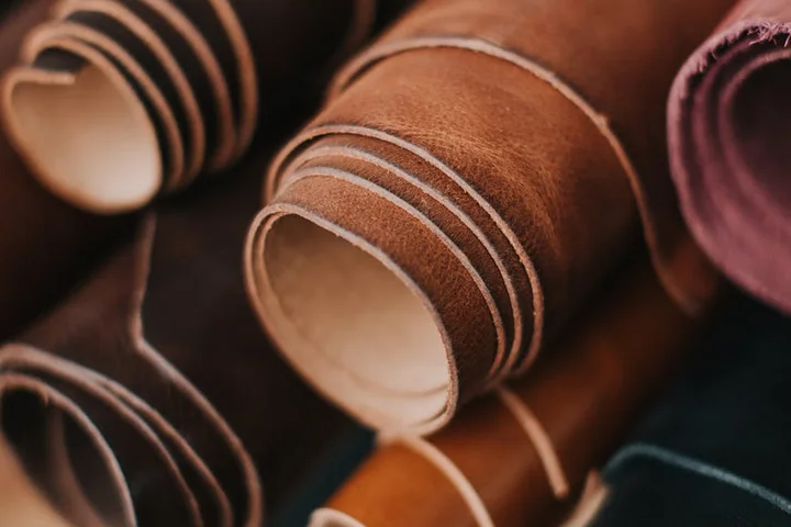 Close-up of stacked leather strips and hides in warm brown tones.