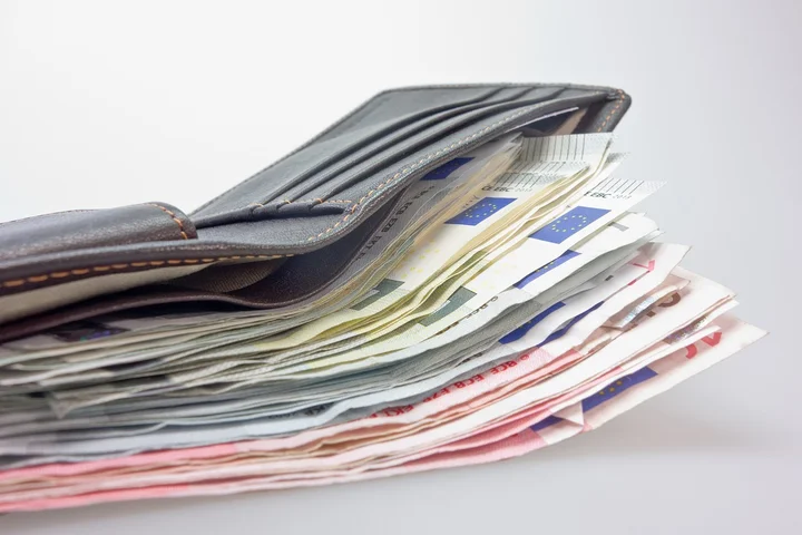 Leather wallet filled with cash on a light background