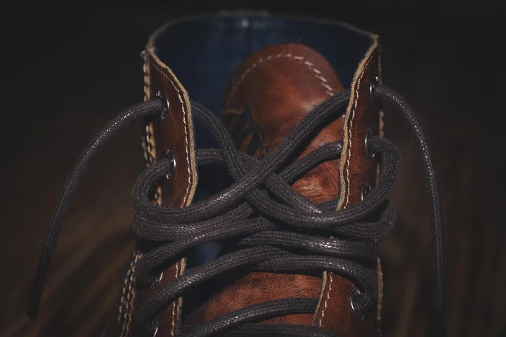 Close-up of a brown leather boot with black laces and visible stitching