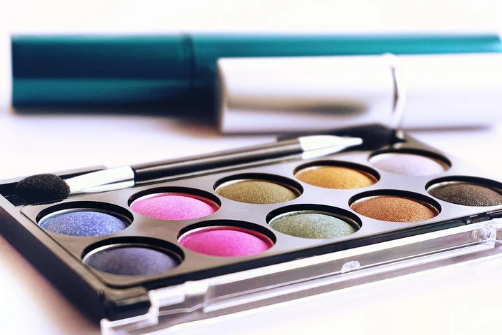 Open makeup palette with colorful powders and makeup brushes on a white surface