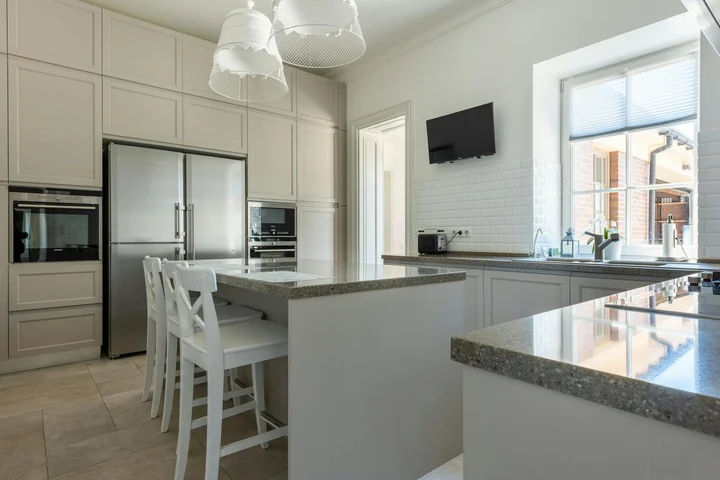 Bright modern kitchen with white cabinetry and stainless steel appliances, granite countertops, and a large window