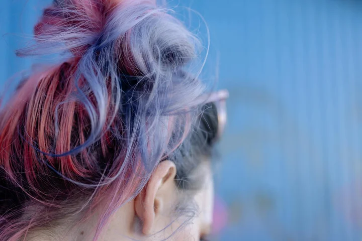 Close-up of a person’s head from behind with vivid blue, purple, and pink hair, illustrating hair dye colors that can transfer onto fabrics.