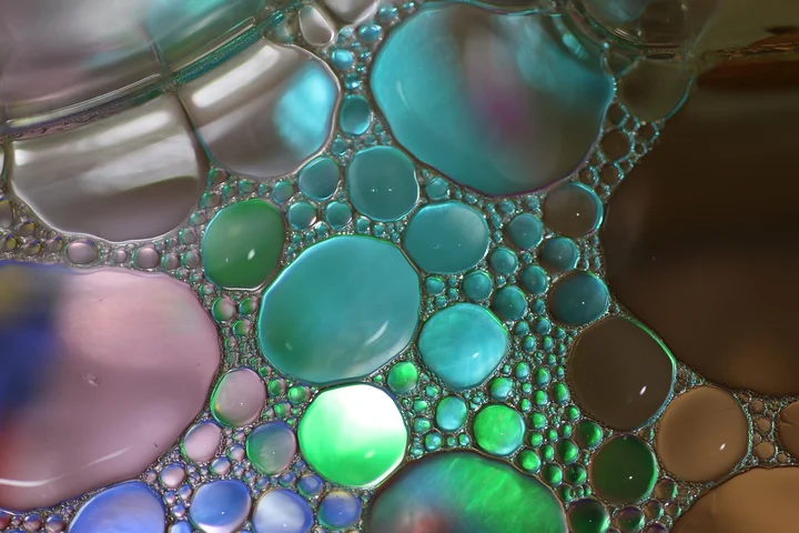 Close-up of colorful oil droplets and bubbles on a liquid surface.