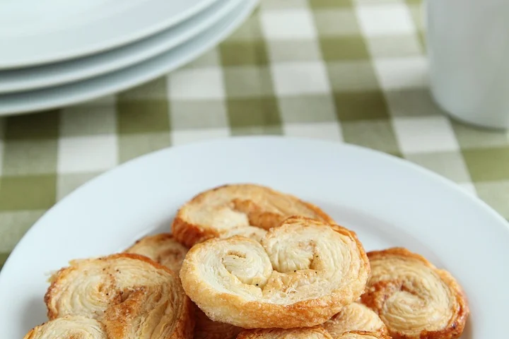Plate of palmiers pastries on a white plate with a green-and-white checkered tablecloth