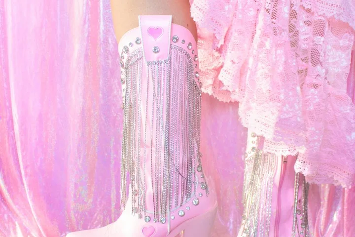Close-up of a pink knee-high boot with fringe and rhinestones