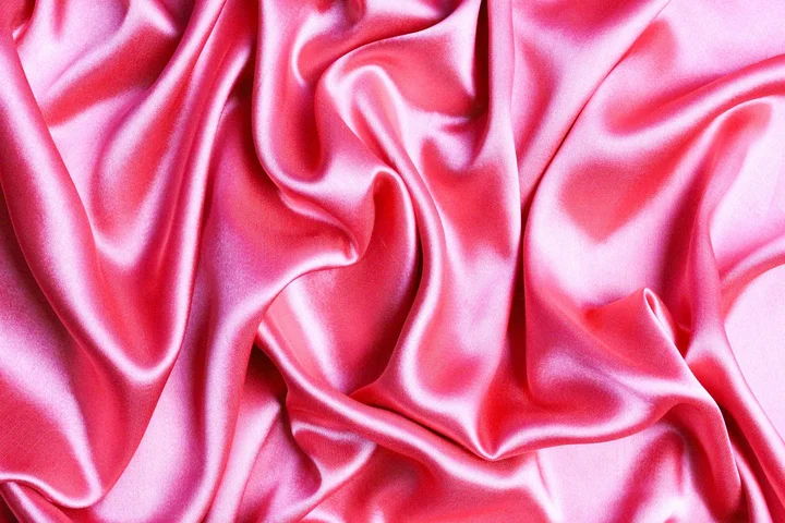 Close-up of pink satin silk fabric with flowing folds