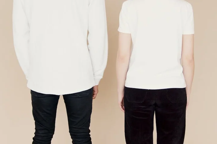 Back view of two people wearing white tops and dark pants