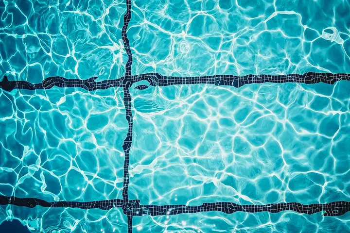Close-up of turquoise pool water over mosaic tile and dark grout lines