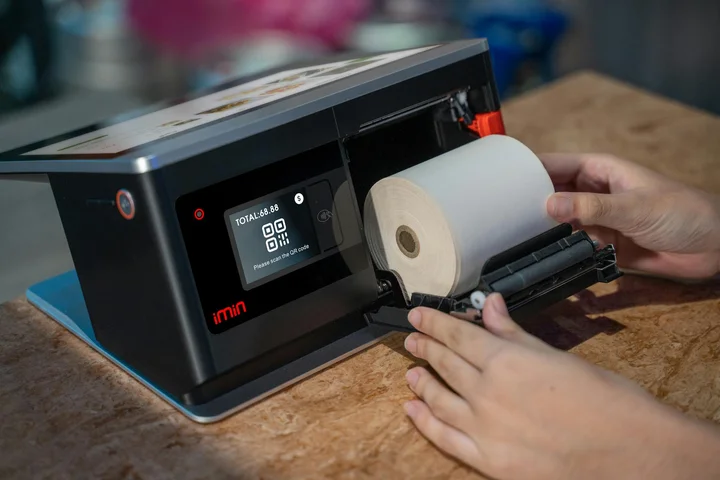 Close-up of hands removing leftover paper from a compact printer to address a jam