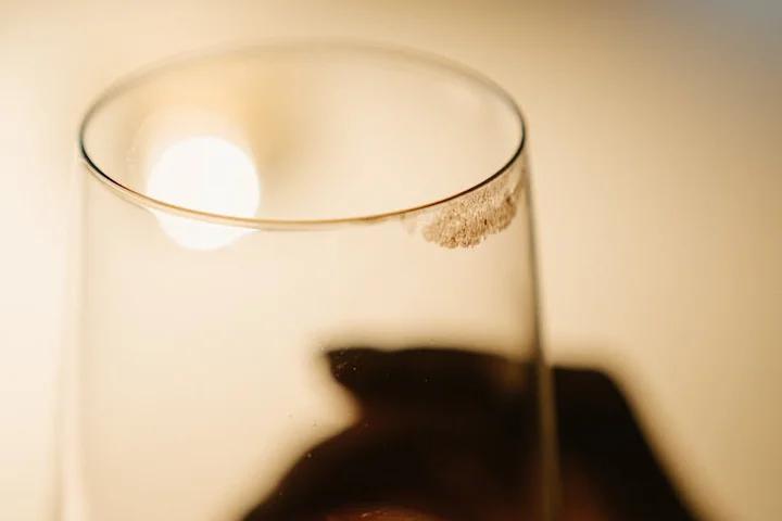 Close-up of a glass with a brown putty stain on the rim.