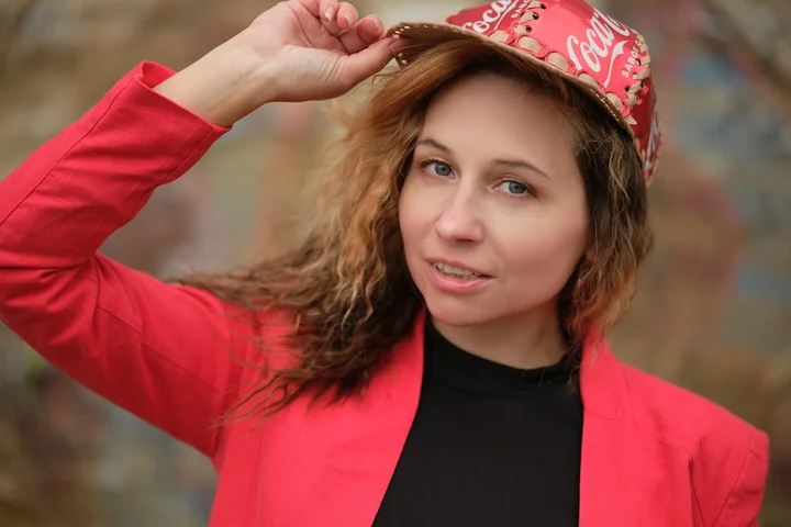 Person wearing a red jacket adjusts a red Coca-Cola branded cap