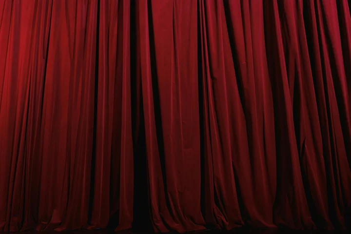 Red velvet theater curtains hanging in a stage setting