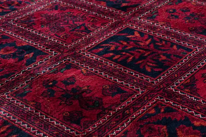 Close-up of a red patterned carpet showing intricate woven fibers and geometric borders.