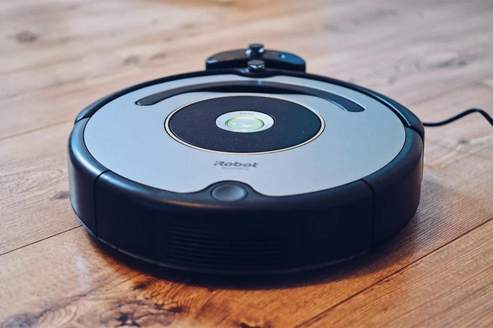 Robotic vacuum on a hardwood floor, illustrating the post-treatment drying stage and odor-check process.