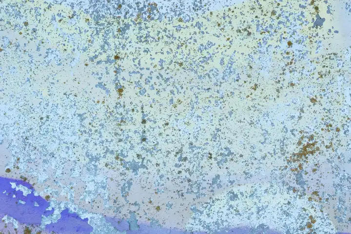 Close-up of a blue-painted surface with scattered rust spots and chipped paint