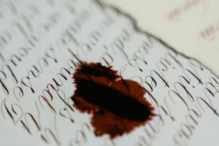 Close-up of a brown stain on a sheet of handwritten cursive text