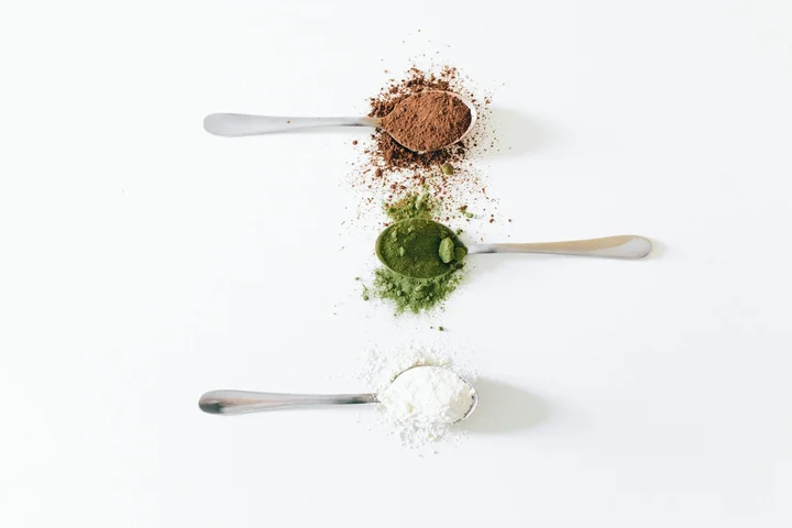 Three spoons arranged vertically on a white surface with powders: brown on top, green in the middle, and white at the bottom, illustrating different cleaners and the potential for scratching.