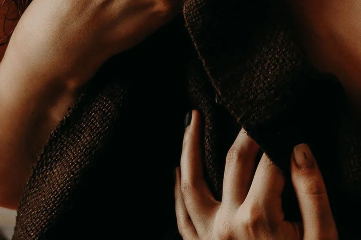 Close-up of hands gripping dark fabric, showing skin and textile where dye stains can occur.