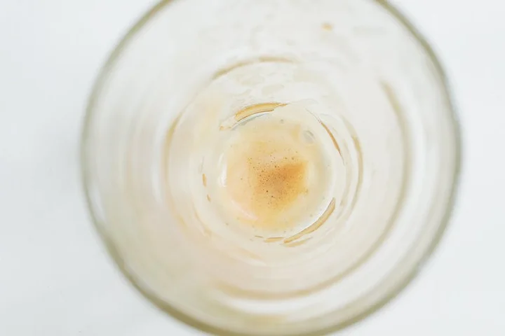 Top-down view of a clear glass with a light brown coffee stain at the bottom.