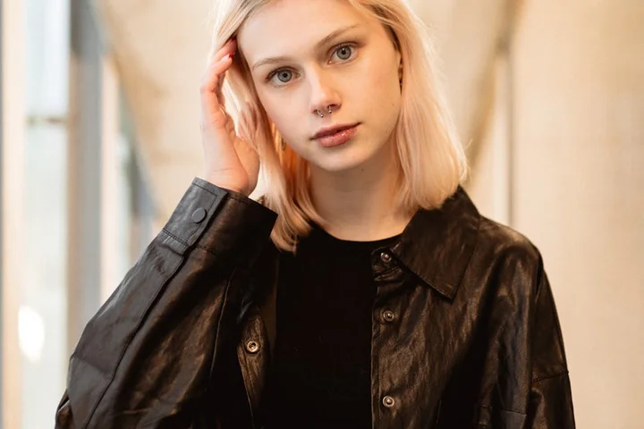 Person wearing a black leather jacket in a bright indoor setting.
