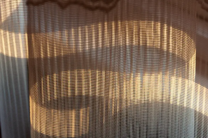 Sunlit sheer curtains with visible wrinkles and folds