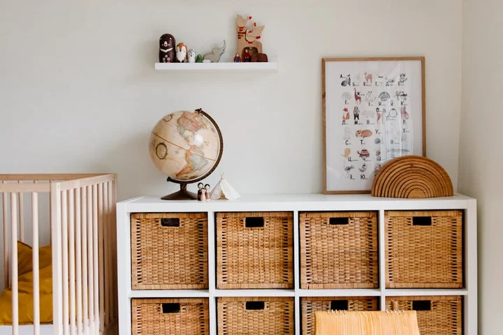 Interior scene with white cubby storage and woven baskets, globe, and framed chart, illustrating a setting to discuss rug materials and wrinkle-removal methods.