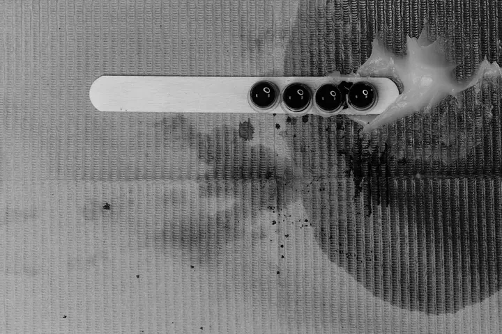 Close-up of a textured carpet with dark paint stains and a white cleaning tool resting on top, illustrating the difference between carpet and car interior surfaces.