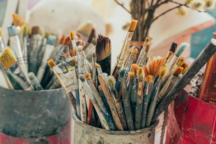 Close-up of paintbrushes and staining tools in cups.