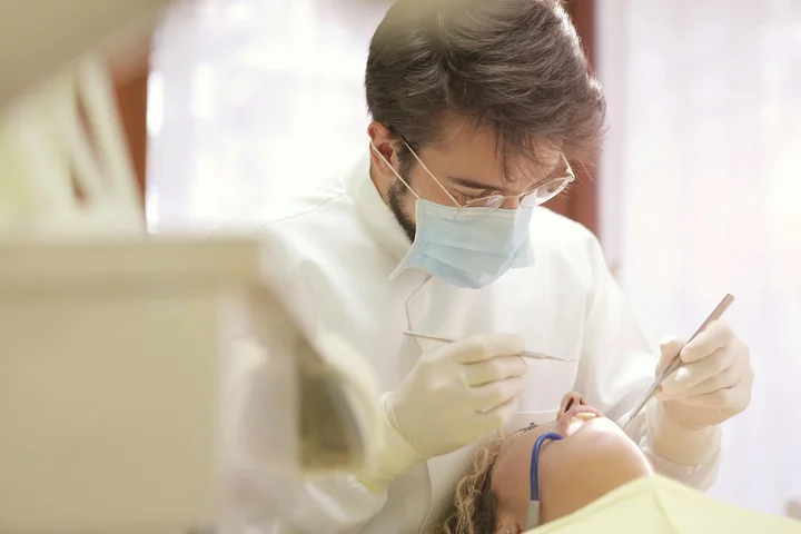 Dentist wearing a mask and gloves performing a dental procedure on a patient