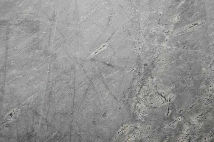 Close-up of a gray terrazzo floor texture with scratches and imperfections.