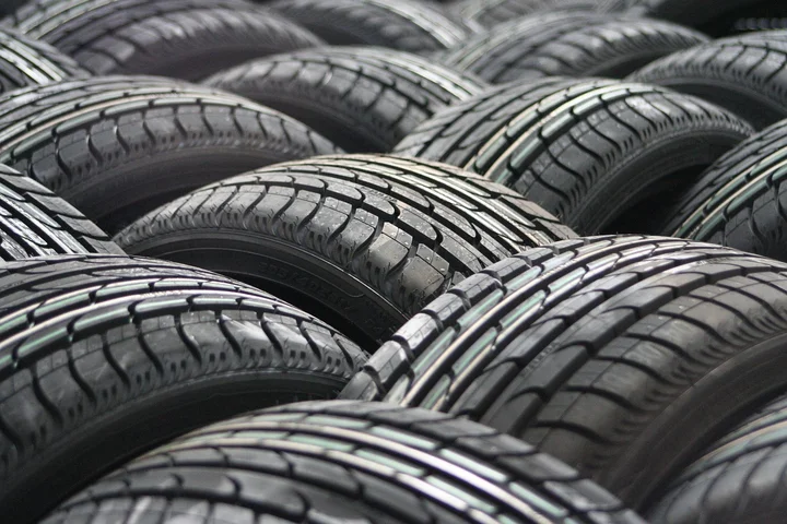 Close-up of stacked car tires, highlighting wheel wells and undercarriage areas prone to tar and road grime.