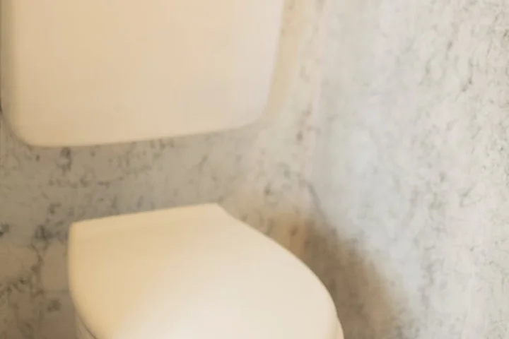 White toilet with closed lid in a bathroom with marble-patterned walls