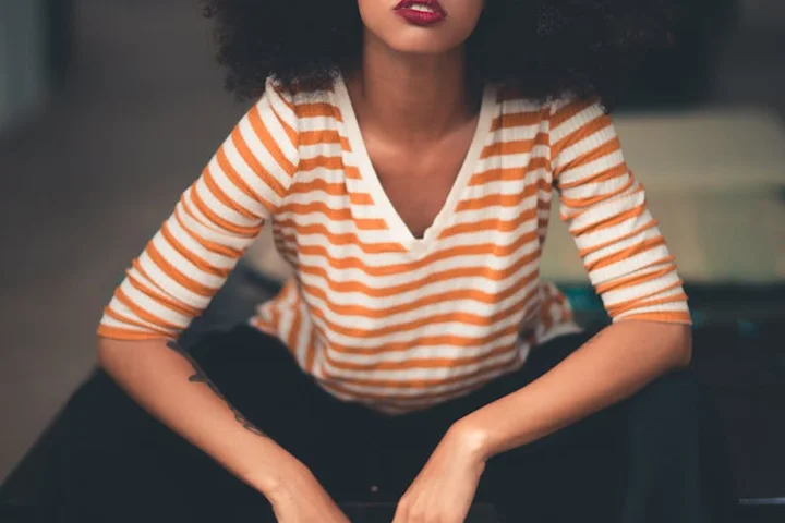 Person wearing an orange-and-white striped shirt seated, illustrating a stain-removal guide.