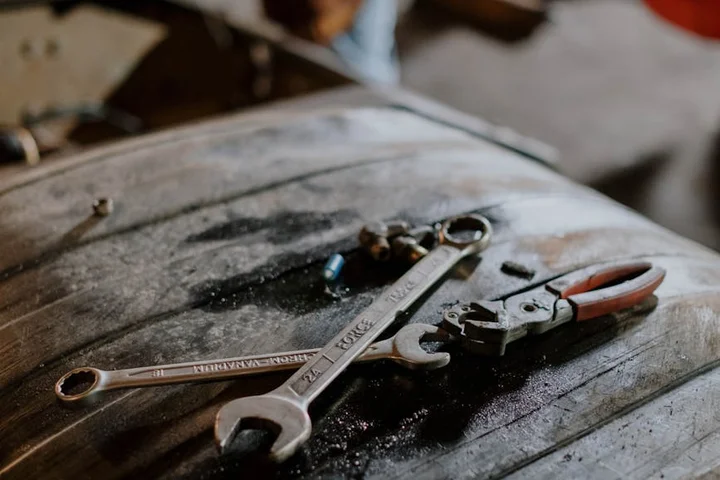 Wrenches and pliers laid out on a dark, grease-stained wooden workbench