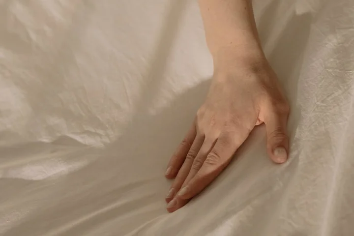 A hand smoothing a white bedsheet