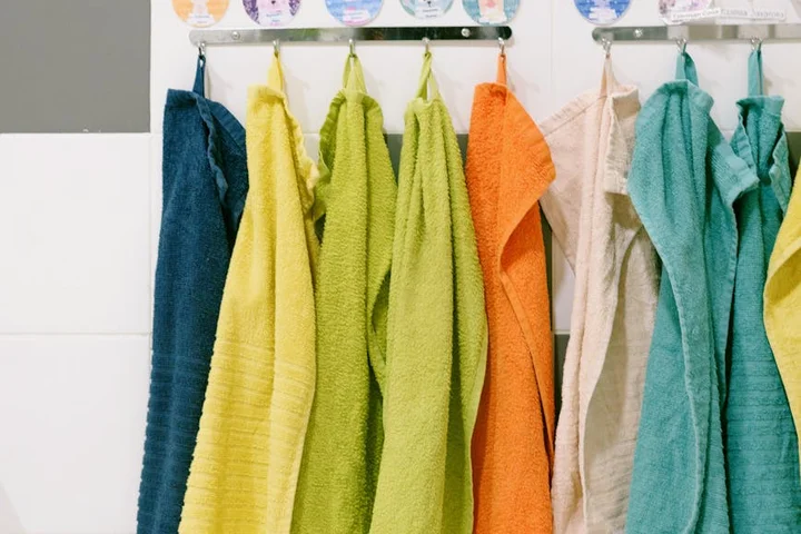 Row of colorful towels hanging on a towel rack in a bathroom.