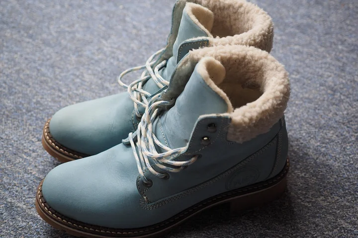 Light blue Ugg-style boots with sheepskin lining resting on a textured carpet