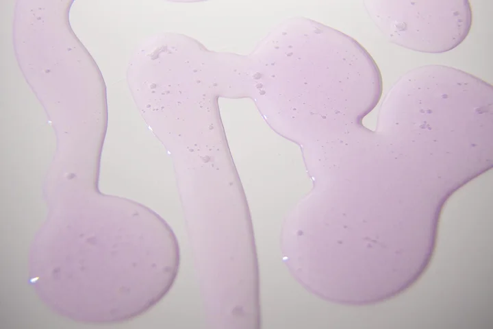 Close-up of irregular pink liquid stains on a white surface, representing common dye spills.