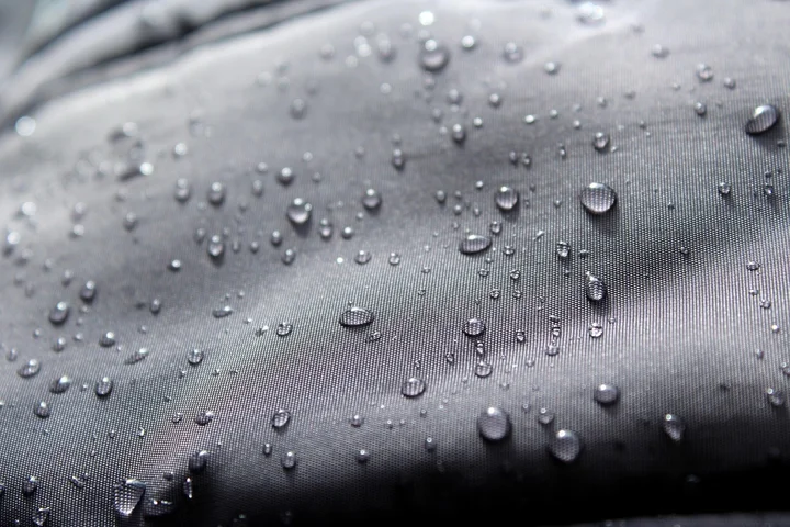 Close-up of dark upholstery fabric with scattered water droplets.
