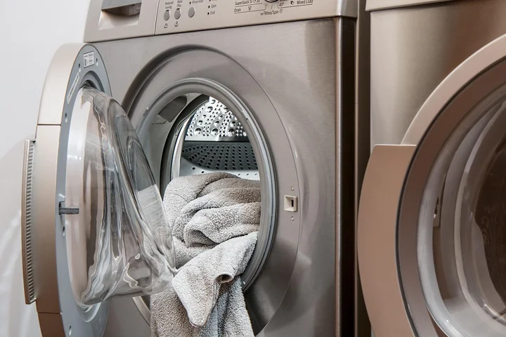 Front-load washing machine with its door open and towels inside.
