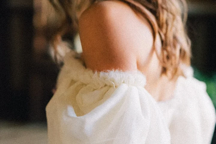 Close-up of an off-the-shoulder wedding dress sleeve in white fabric with soft textures.