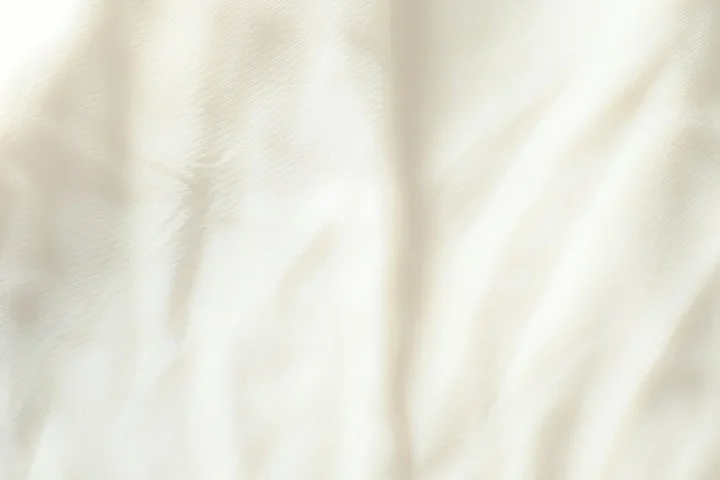 Close-up of wrinkled pale white fabric, signaling non-clothing surfaces in stain-removal quick guides.