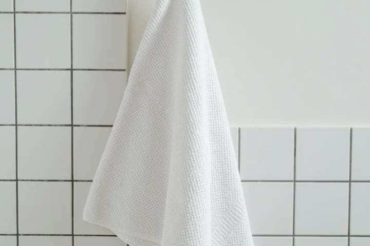 White towel hanging on a tiled bathroom wall