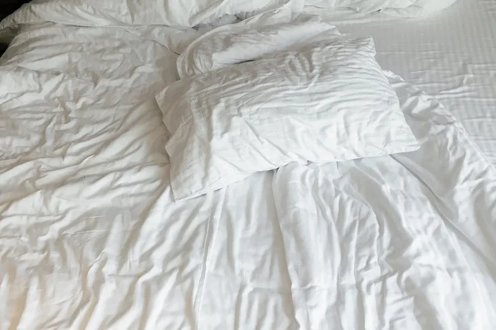White bed with crumpled sheets and pillows