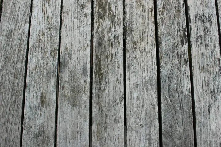 Close-up of weathered wooden floor planks with dark stain marks.