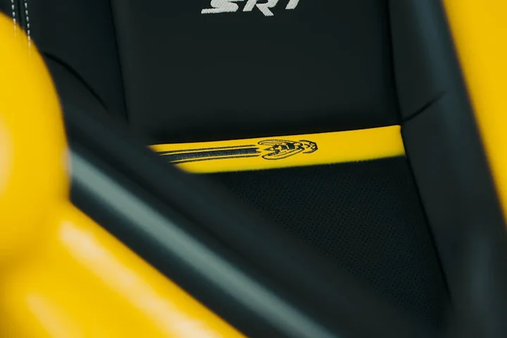 Close-up of a yellow seat belt against black car upholstery inside a sports car.